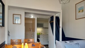 A compact living space with a dining area, kitchenette, and a sofa with a pillow. - Atlantique 165 (La Faute-sur-Mer)