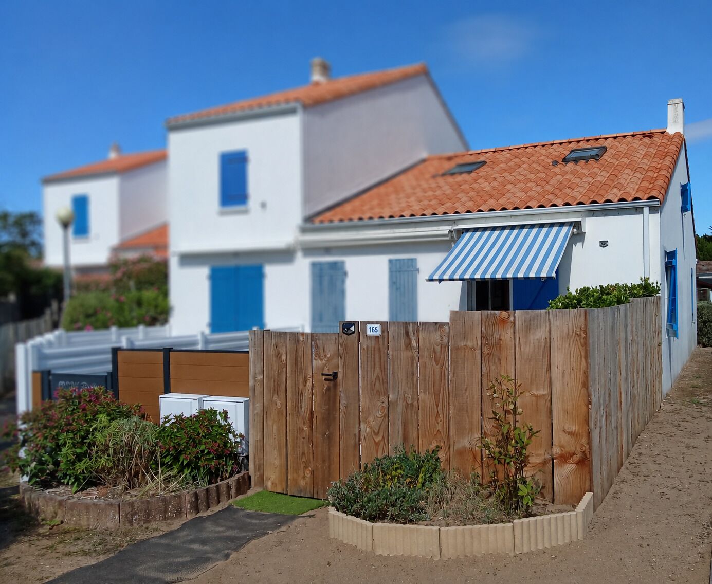 A residential area with white houses, red-tiled roofs, and wooden fences.