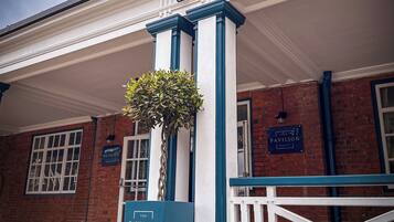 A building with a white facade, blue trim, and a sign reading "The Pavilion Bisley."