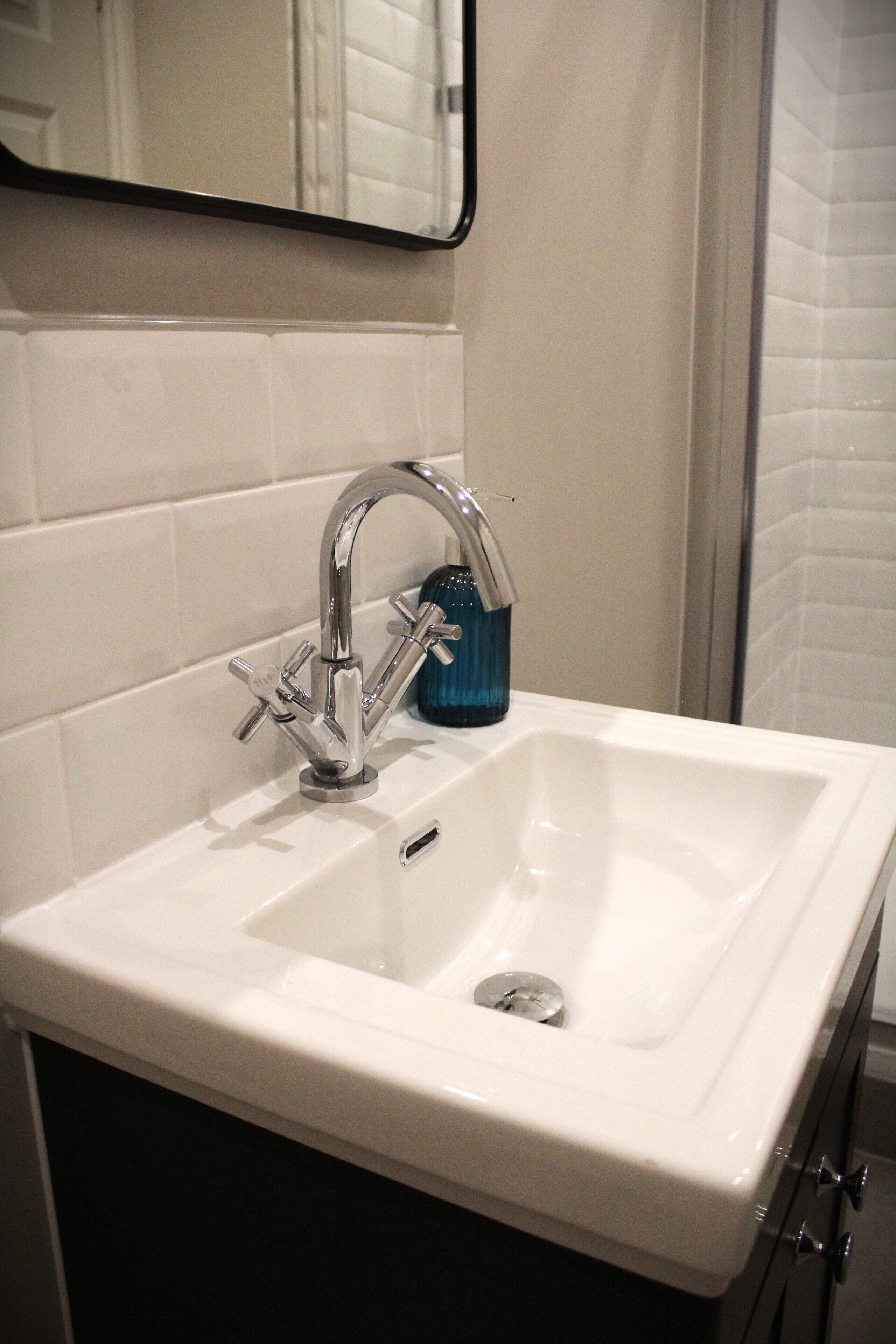 A bathroom with a white sink, chrome faucet, and a blue soap dispenser.