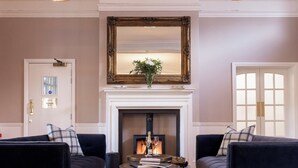 A room with a fireplace, two sofas, a mirror, and a door labeled "ROOMS 5-15". - The Pavilion Bisley (Woking)