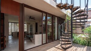 Een modern huis met een wenteltrap, schuifglaasdeuren en een houten terras.