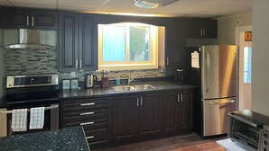 A modern kitchen with dark cabinets, stainless steel appliances, and a window providing natural light.