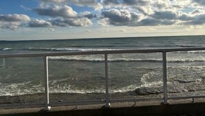 A coastal view with a railing in the foreground and a clear sky with clouds.