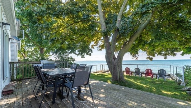 A wooden deck with a table and chairs, overlooking a body of water.