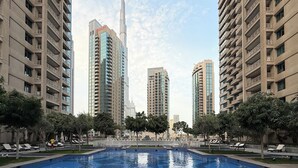 Un quartier résidentiel moderne, avec de grands immeubles, une piscine et des chaises longues.