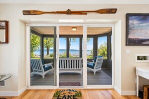 Ein Zimmer mit einer Schiebetür zu einem Deck mit zwei Stühlen und Seeblick.