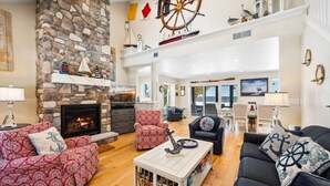 A spacious living room with a stone fireplace, nautical decor, and a view of the sea.