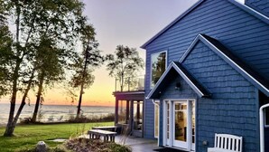 A coastal house with a covered patio, a bench, and a view of the ocean.