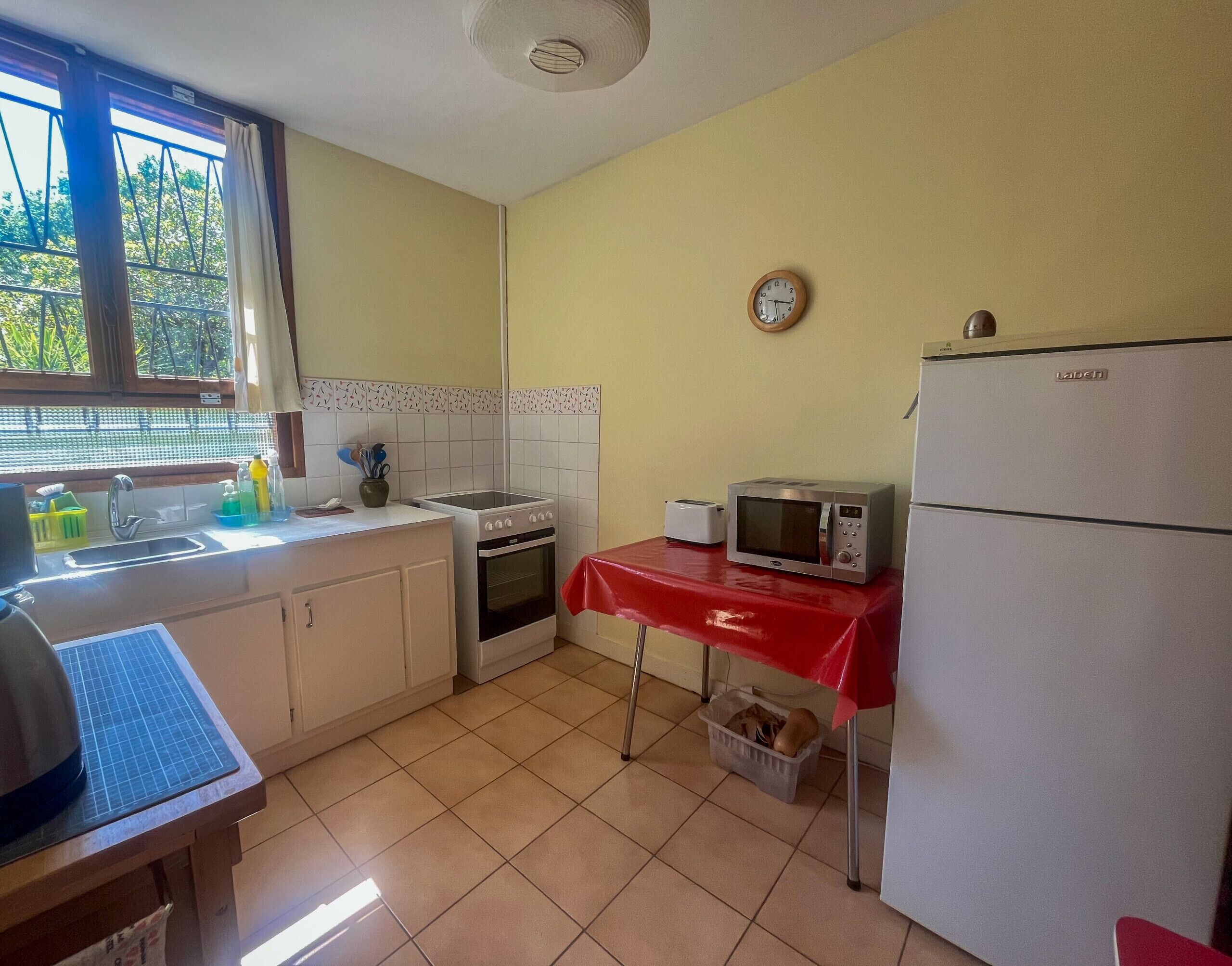 A compact kitchen with basic appliances, a sink, and a window with a view of greenery.