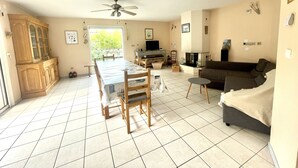 A spacious living area with a dining table, a sofa, and a television. - Villa Colombe by Agence Bru - 453196 (Carcans)