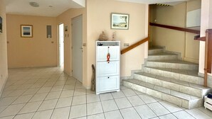 A hallway with a staircase leading to a landing. - Villa Colombe by Agence Bru - 453196 (Carcans)