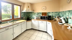 A kitchen with white cabinets, a microwave, a toaster, and a coffee maker. - Villa Colombe by Agence Bru - 453196 (Carcans)