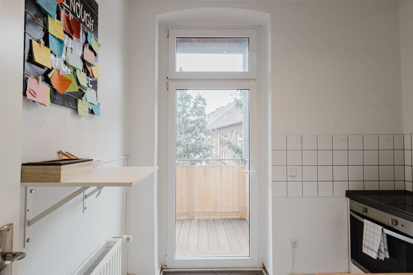 Eine Küche mit Fenster, weißem Regal und gefliestem Fliesenspiegel.