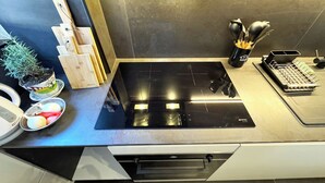Eine moderne Küche mit einem schwarzen Herd, Holzschneidebrettern, einem Blumentopf und einem Geschirrgestell.