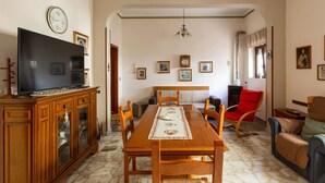 A dining area with a wooden table, chairs, and a television on a cabinet.