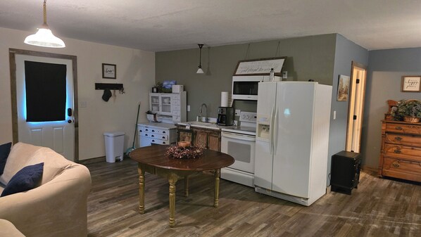 A compact living space with a kitchenette, a dining table, and a sofa. - Hayfield Cabin (Niota)