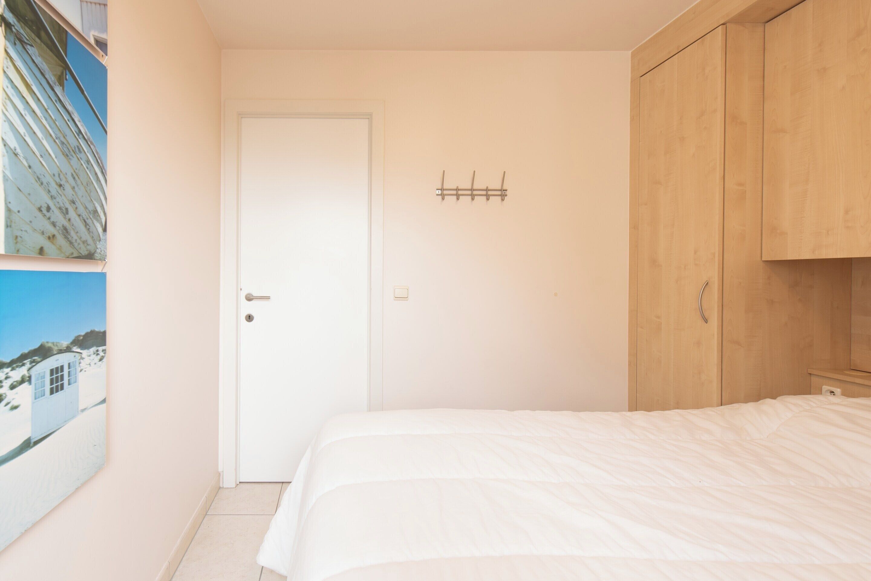 A bedroom with a bed, a door, and wooden cabinets.