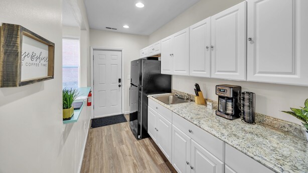 A modern kitchen with white cabinets, a stainless steel refrigerator, and a coffee maker. - Cozy 2 Bedroom Getaway (Covington)