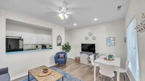 A modern kitchen with white cabinets, a built-in oven, and a large TV. - Cozy 2 Bedroom Getaway (Covington)