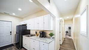 A modern kitchen with white cabinets, a black refrigerator, and a granite countertop. - Cozy 2 Bedroom Getaway (Covington)