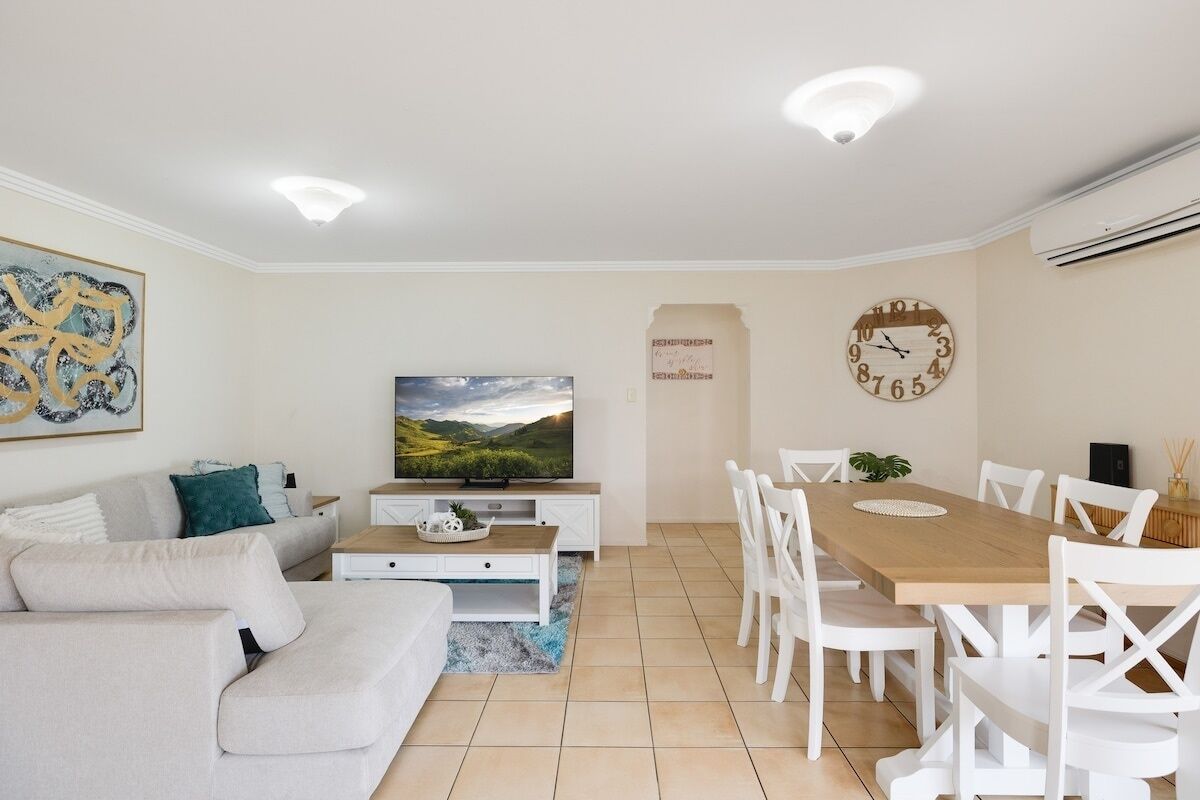 Un salon moderne comprenant un canapé, un tél éviseur, une table à manger et des chaises.