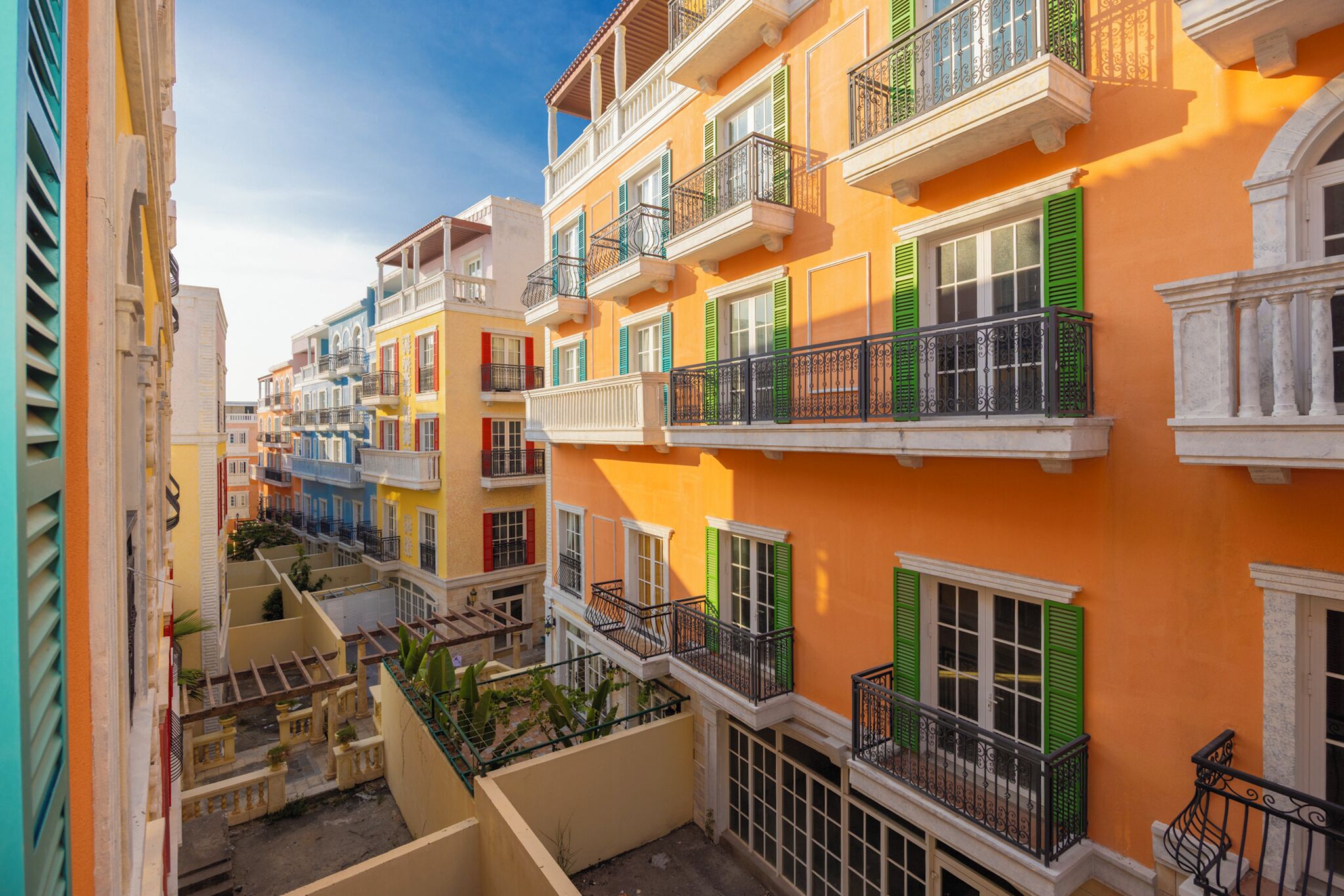 Un edificio de varios pisos con balcones, un patio y una escalera.