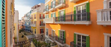Un edificio de varios pisos con balcones, un patio y una escalera.