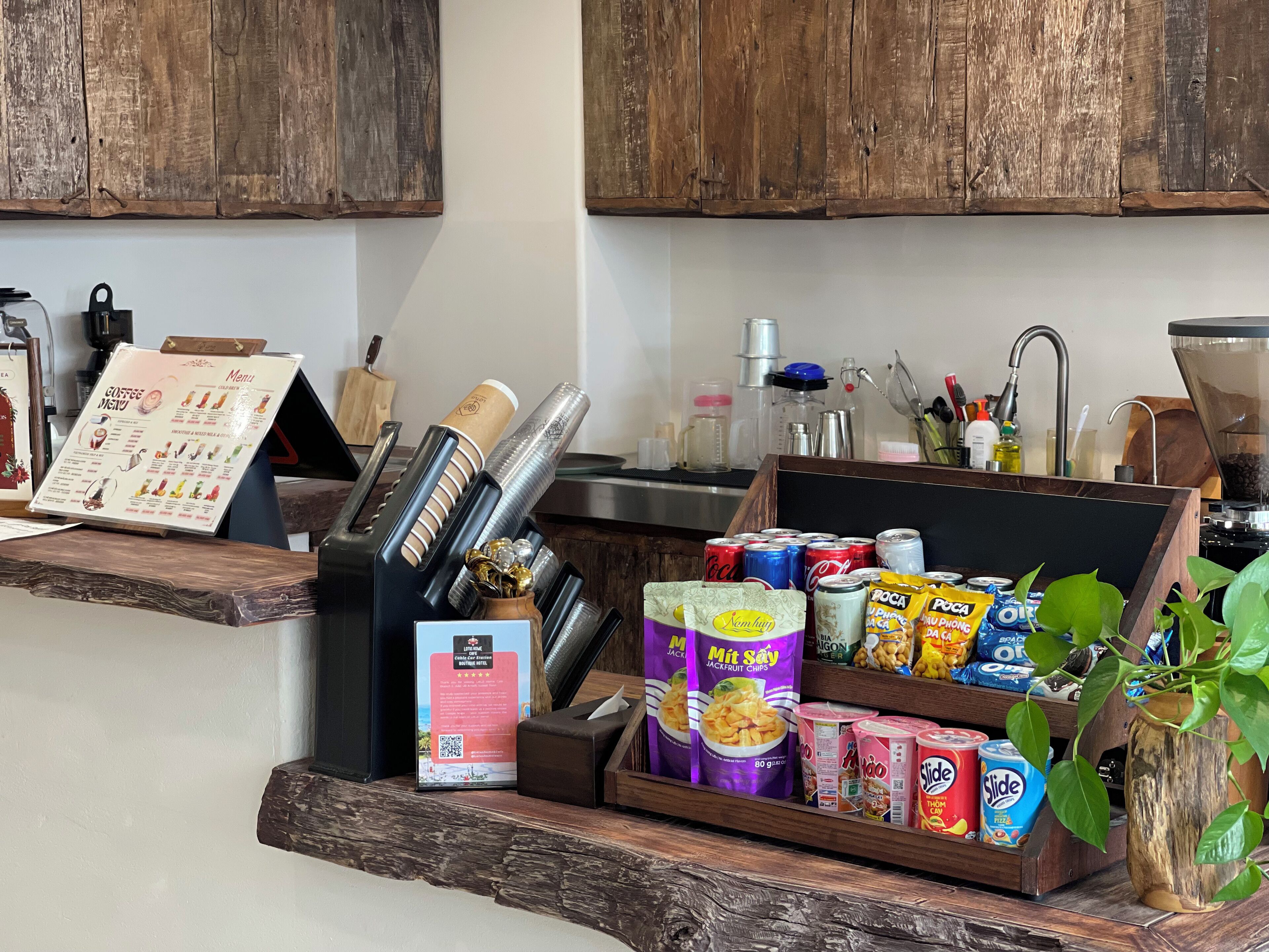 A coffee station with a menu, various coffee machines, and a selection of snacks and drinks.