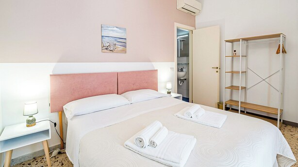Ein Hotelzimmer mit Bett, Nachttisch, Schrank und einem Bild an der Wand.
