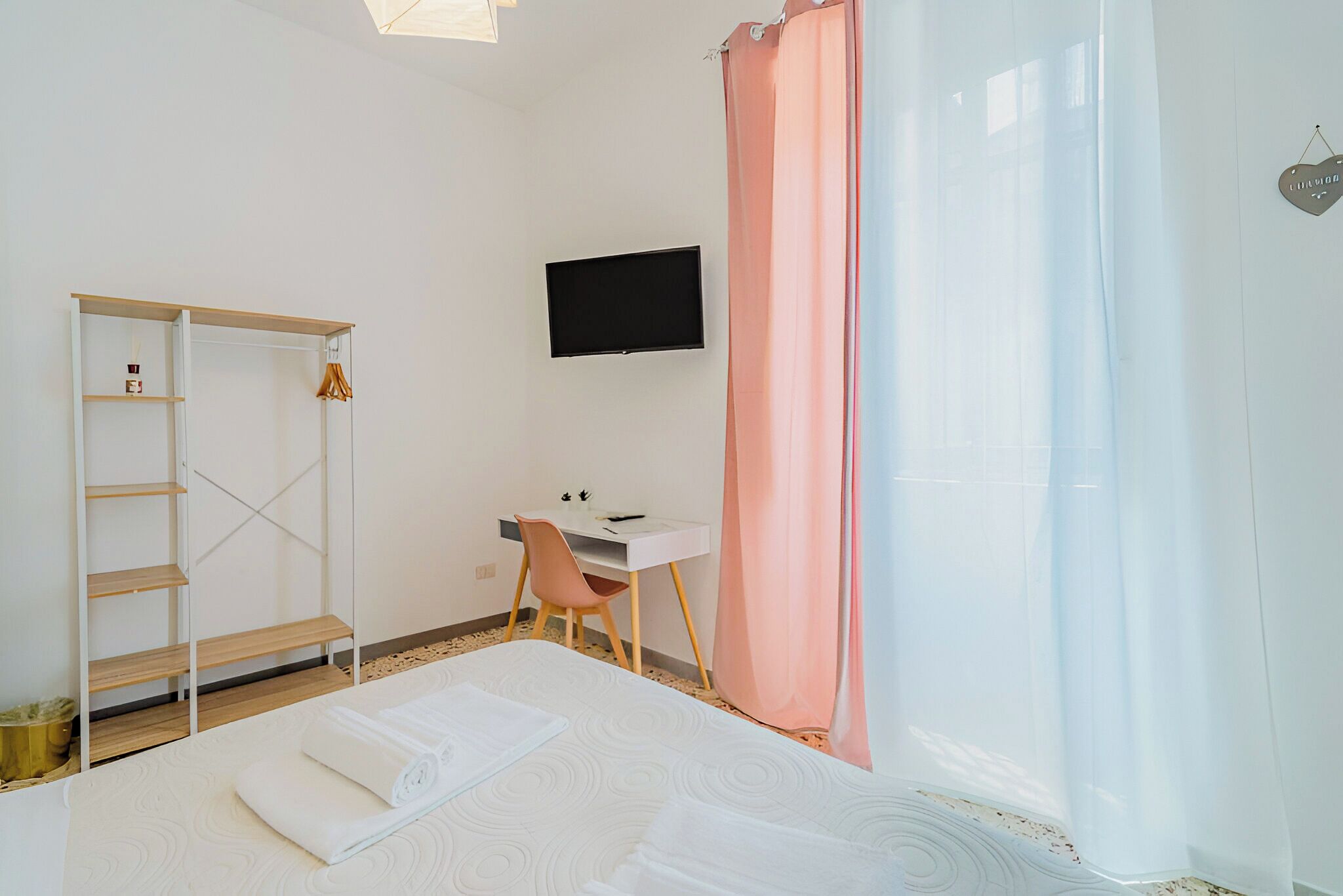 Ein Schlafzimmer mit Bett, Schreibtisch, Stuhl, Fernseher und Kleiderschrank.