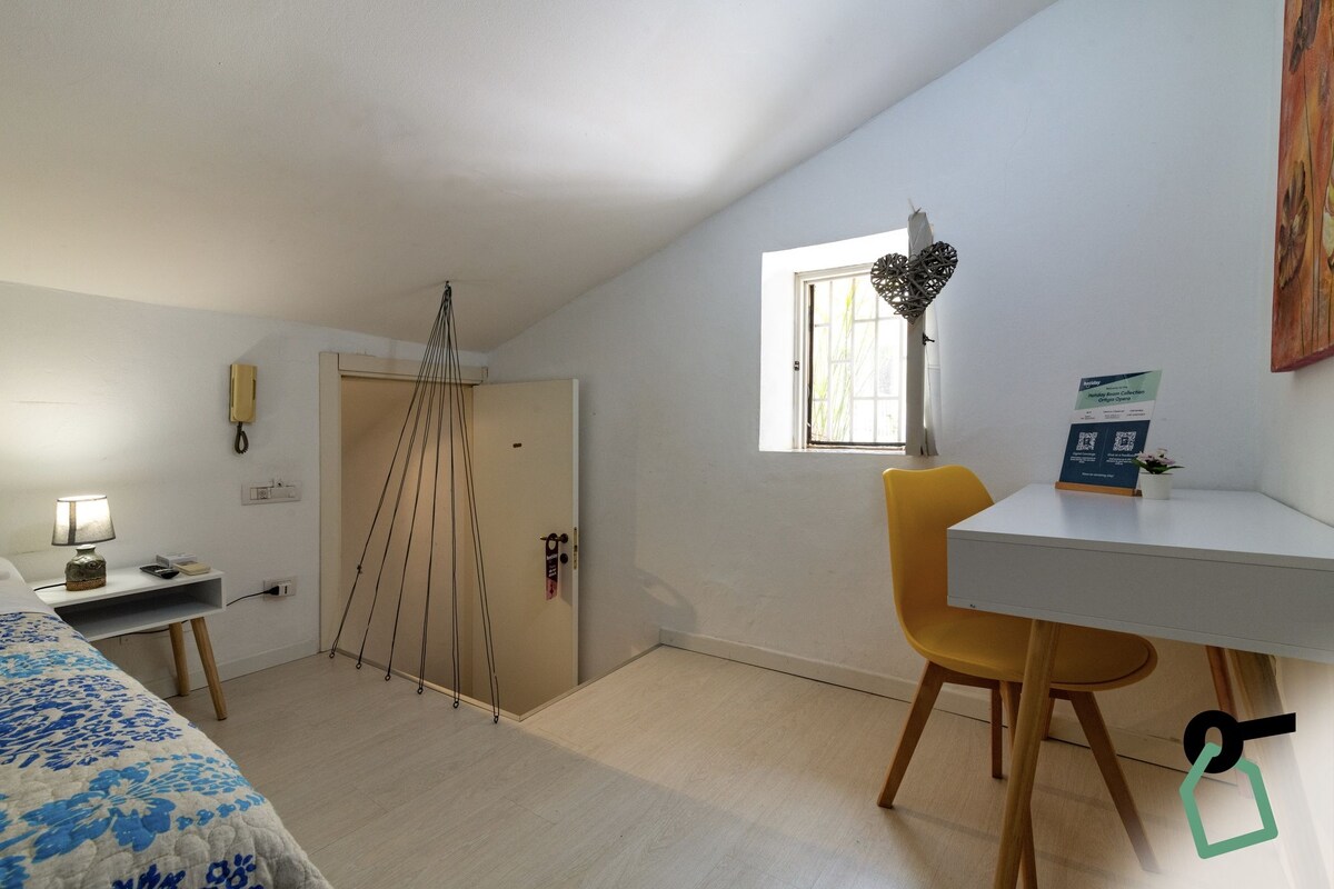 A room with a bed, a desk, a chair, a window, and a door.