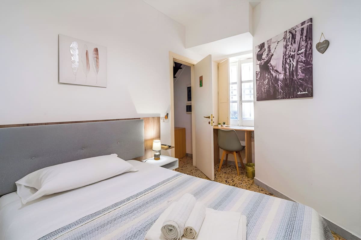 A hotel room with a bed, a desk, and a chair.