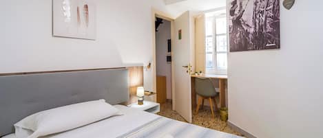 A hotel room with a bed, a desk, and a chair.