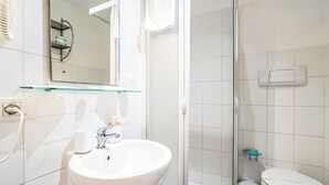 Une salle de bain moderne avec une douche à parois de verre, un lavabo blanc avec un miroir et des toilettes.