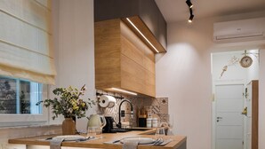 A modern kitchen with wooden cabinets, a central island, and two bar stools. - Northern Blues (Rijeka)
