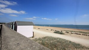 Una fila di cabine sulla spiaggia con un sentiero sabbioso che conduce alla spiaggia.