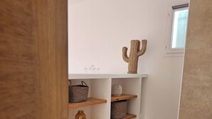 Un baño moderno con una bañera blanca, estantes de madera con cestas y una decoración de cactus, además de una alfombra color beige.