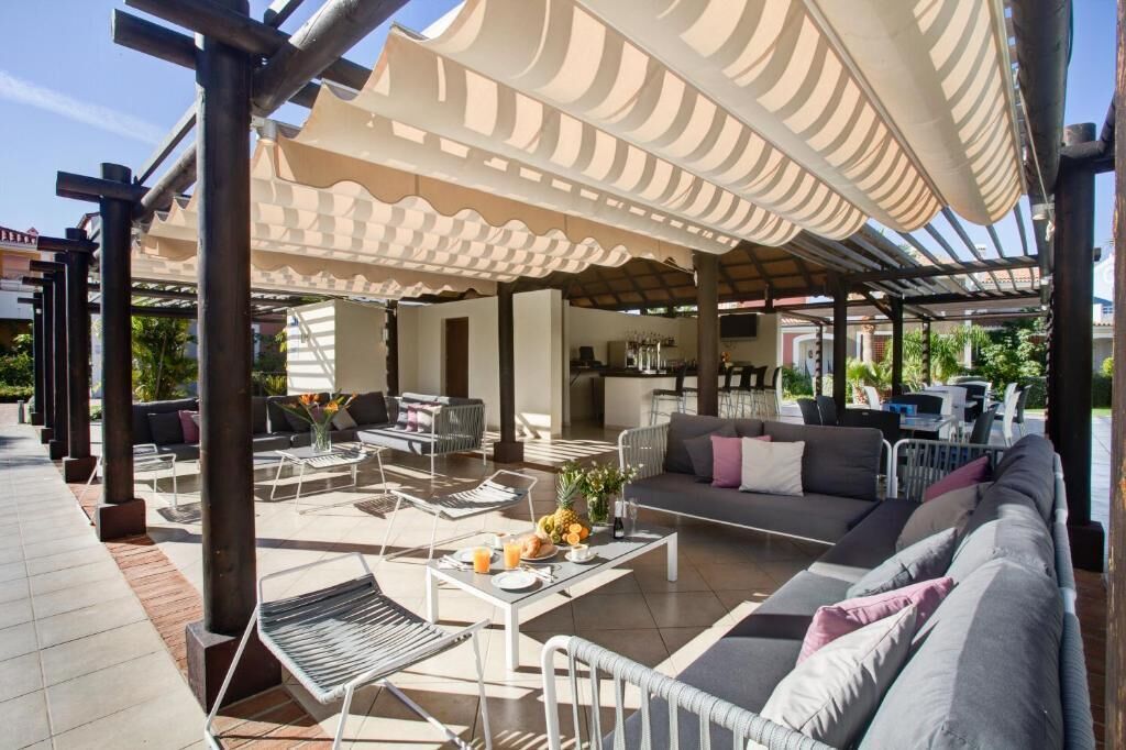 An outdoor patio area with a covered seating area, a bar, and a pool.