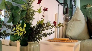 A living room with a round black table, a green vase with flowers, a white sofa, and a wall with framed pictures. - JUPAS° | Premium Apartments - Kylltalperle (Kordel)