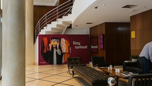 A modern lobby with a marble column, a staircase, and a seating area with a sofa and a table. - Elegance Suítes Higienópolis (Sao Paulo)