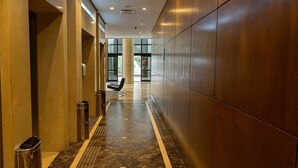 A modern hallway with a marble floor, a trash bin, and a bench. - Elegance Suítes Higienópolis (Sao Paulo)