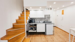 Cocina compacta con escaleras de madera, un microondas, un lavabo y un refrigerador pequeño.