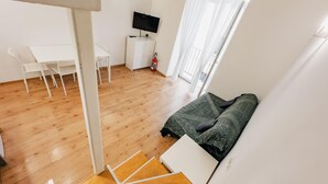 Una sala moderna con un sofá, un televisor y un comedor con sillas y una mesa.
