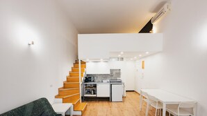 Un espacio habitable pequeño con una escalera que lleva a una zona de cocina.