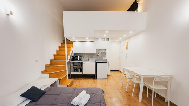 Un estudio compacto con cama, kitchenette y un pequeño comedor.