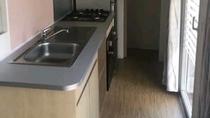 A compact kitchen with a sink, stove, and cabinets. - Mobile home 300m from the beach (Saint-Hilaire-de-Riez)