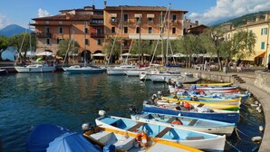 Un puerto deportivo con varias embarcaciones amarradas, un edificio con balcones y un cielo despejado.