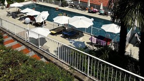 Zona de piscina con sillones de playa y sombrillas, con vista a un lago y montañas.
