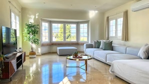 A spacious living room with a large window, a sofa, a coffee table, and a TV.